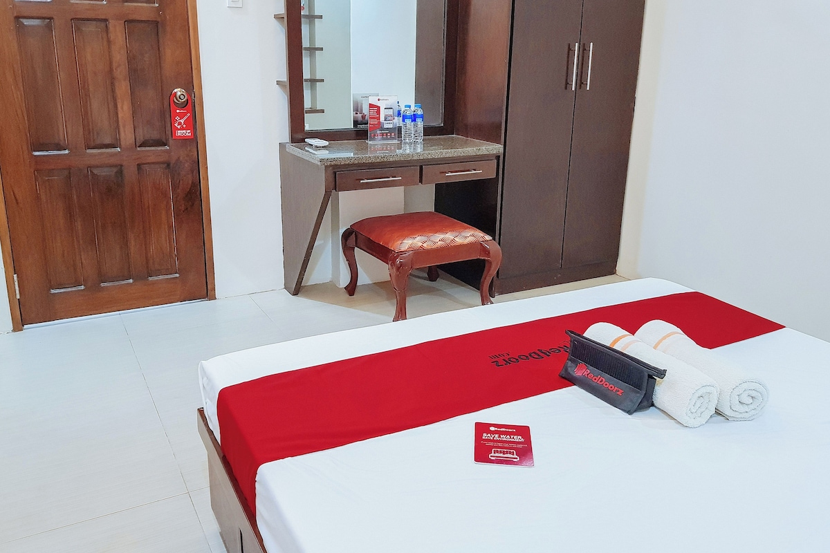Una camera d'albergo con un letto, una scrivania, una sedia, un armadio e uno specchio.