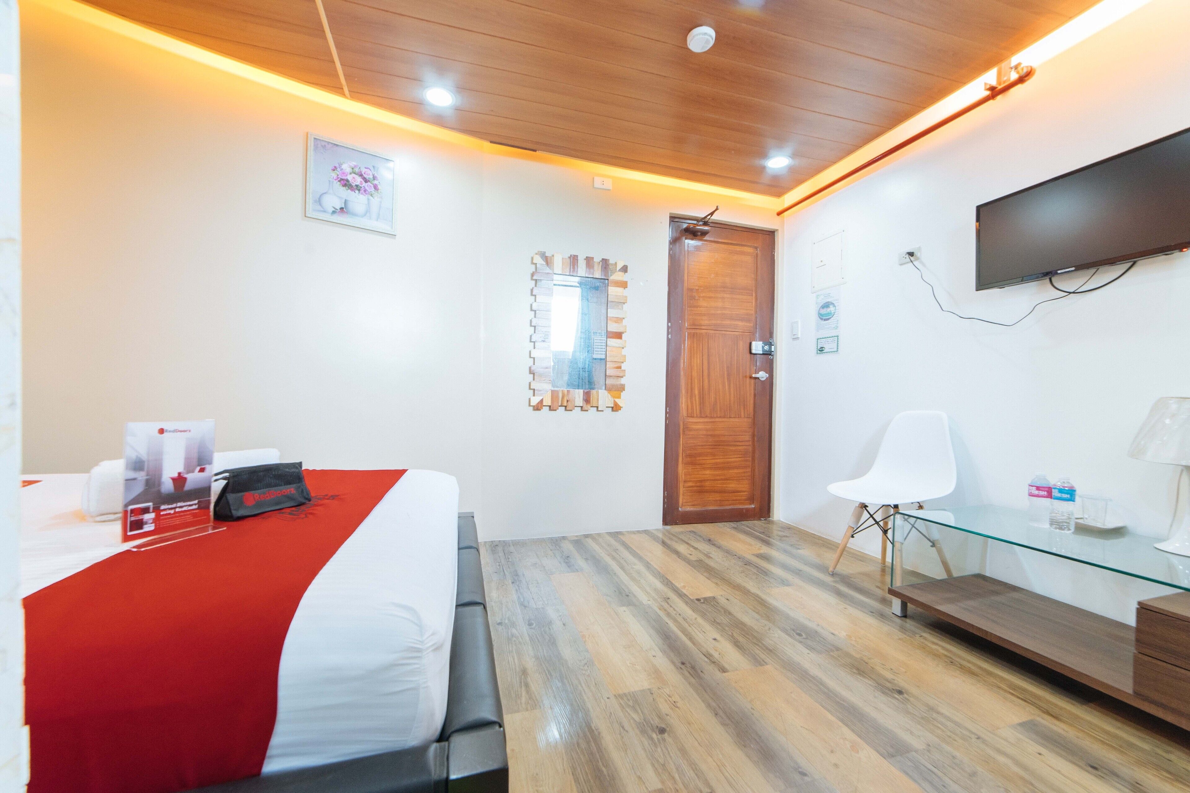 A hotel room with a bed, a desk, a chair, a TV, and a mirror.