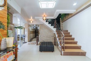 A modern interior with a staircase, a black leather ottoman, and a reception area with a 'SKIP FOR RECEIPT' sign. - RedDoorz @ Lawaan Roxas City (Roxas City)