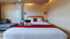 A hotel room with a bed, a red throw blanket, a pillow, and a red and black sign. - RedDoorz @ Lawaan Roxas City (Roxas City)