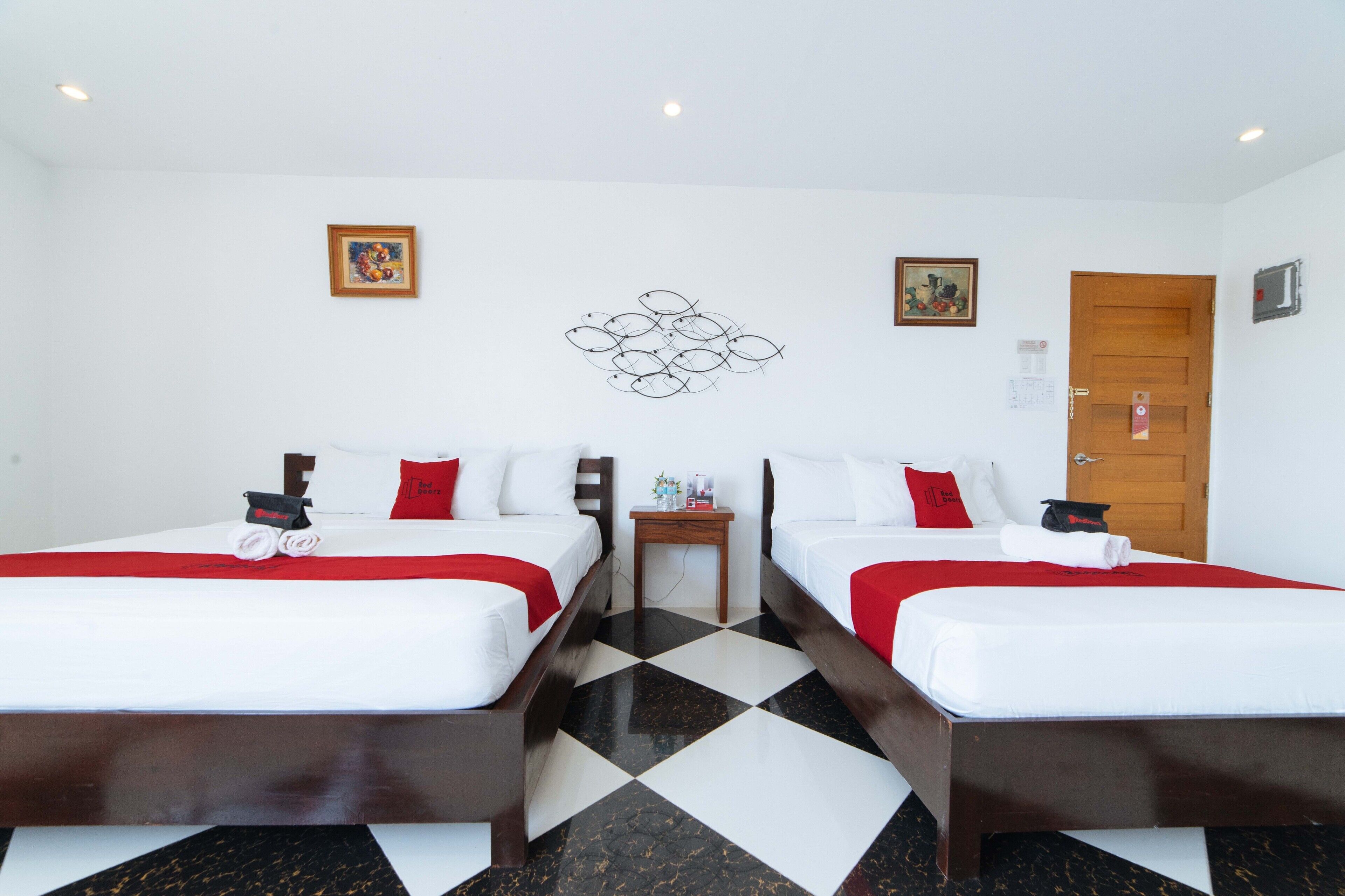 A hotel room with two beds, a wooden floor, and a door with a lock.