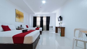 Quarto de hotel com duas camas, televisão, escrivaninha e uma cadeira.