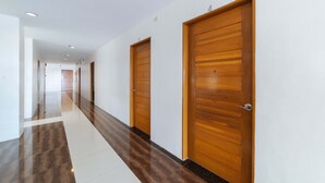 Um corredor com portas de madeira e chão xadrez.