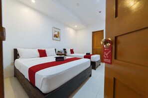 A hotel room with a large bed, two bedside tables, a red throw blanket, and a sign on the door. - RedDoorz Plus @ San Roque Roxas City (Roxas City)