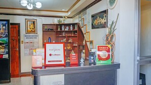 A reception desk with RedDoorz signage, a calendar, and various decorative items. - RedDoorz near Old Tagbilaran Airport (Tagbilaran)