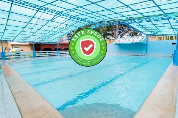 A swimming pool with a safety sign and a blue roof structure. - RedDoorz Premium @ Gabinete Road Palawan (Puerto Princesa)