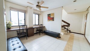 Ein geräumiger Wohnbereich mit Schreibtisch, Stühlen, einer Bank, Deckenventilator und einer Treppe.
