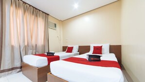 Ein Hotelzimmer mit zwei Einzelbetten, jeweils mit roter Bettdecke und passenden Kissen.