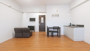 A modern apartment with a living area, a dining table with chairs, a kitchen area, and a door with a security sign. - RedDoorz near SM Manila (Manila)