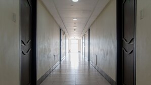 A long, narrow hallway with doors on both sides, a tiled floor, and a ceiling with recessed lighting. - RedDoorz near SM Manila (Manila)