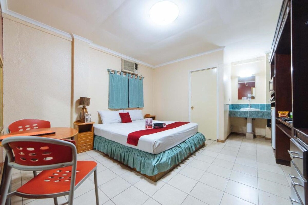 A hotel room with a bed, a desk, a chair, a bathroom, and a TV.