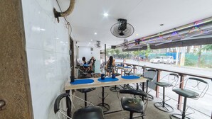 A restaurant with a bar area, multiple chairs, and a view of the street outside. - RedDoorz @ Clarkview 21st Street Angeles City (Angeles City)