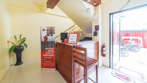 A reception desk with a RedDoor sign, a potted plant, and a fire extinguisher. - Reddoorz @ D Maagma Street - Vaccinated Staff (Kalibo)