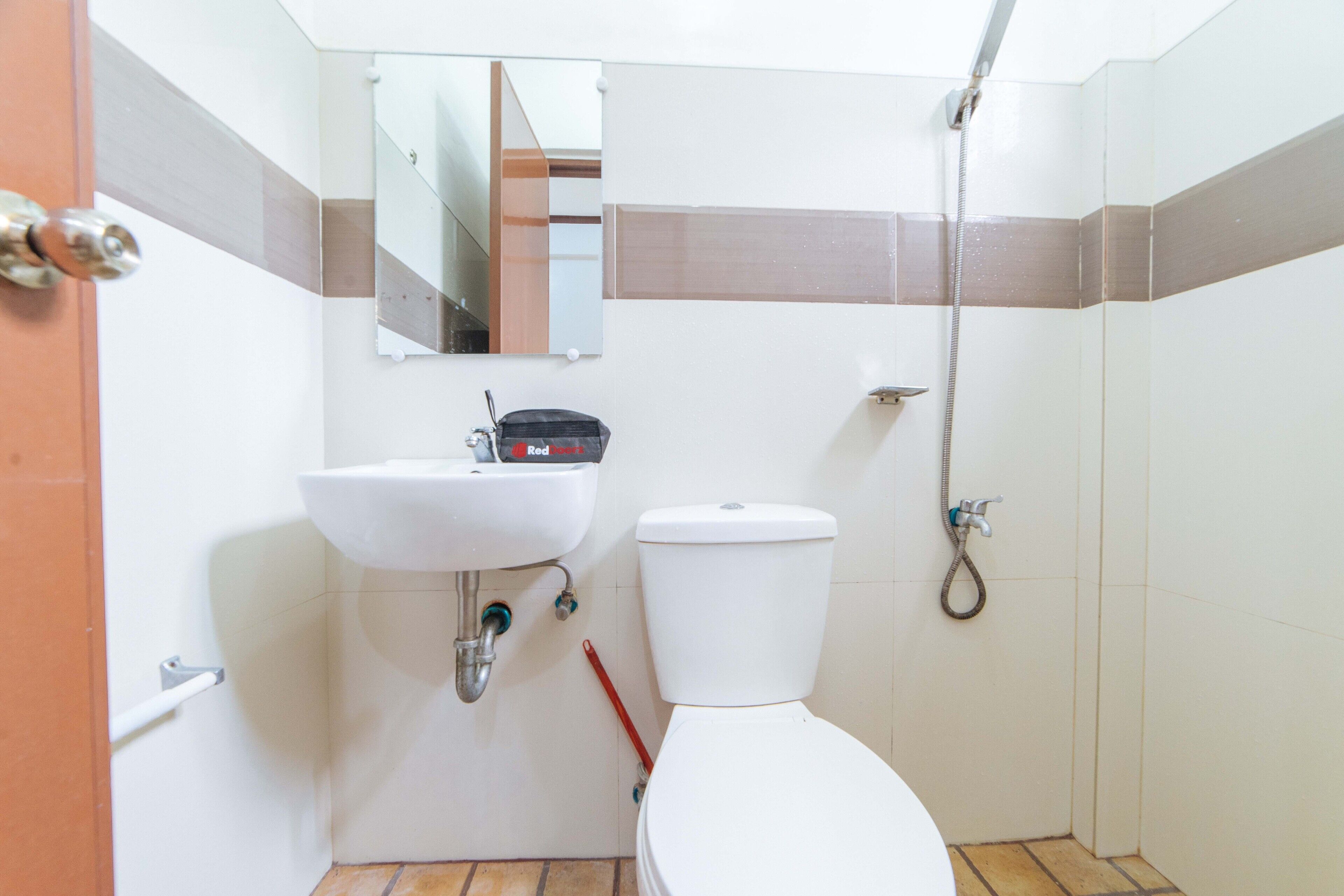 A bathroom with a white sink, a toilet, a shower, and a mirror.