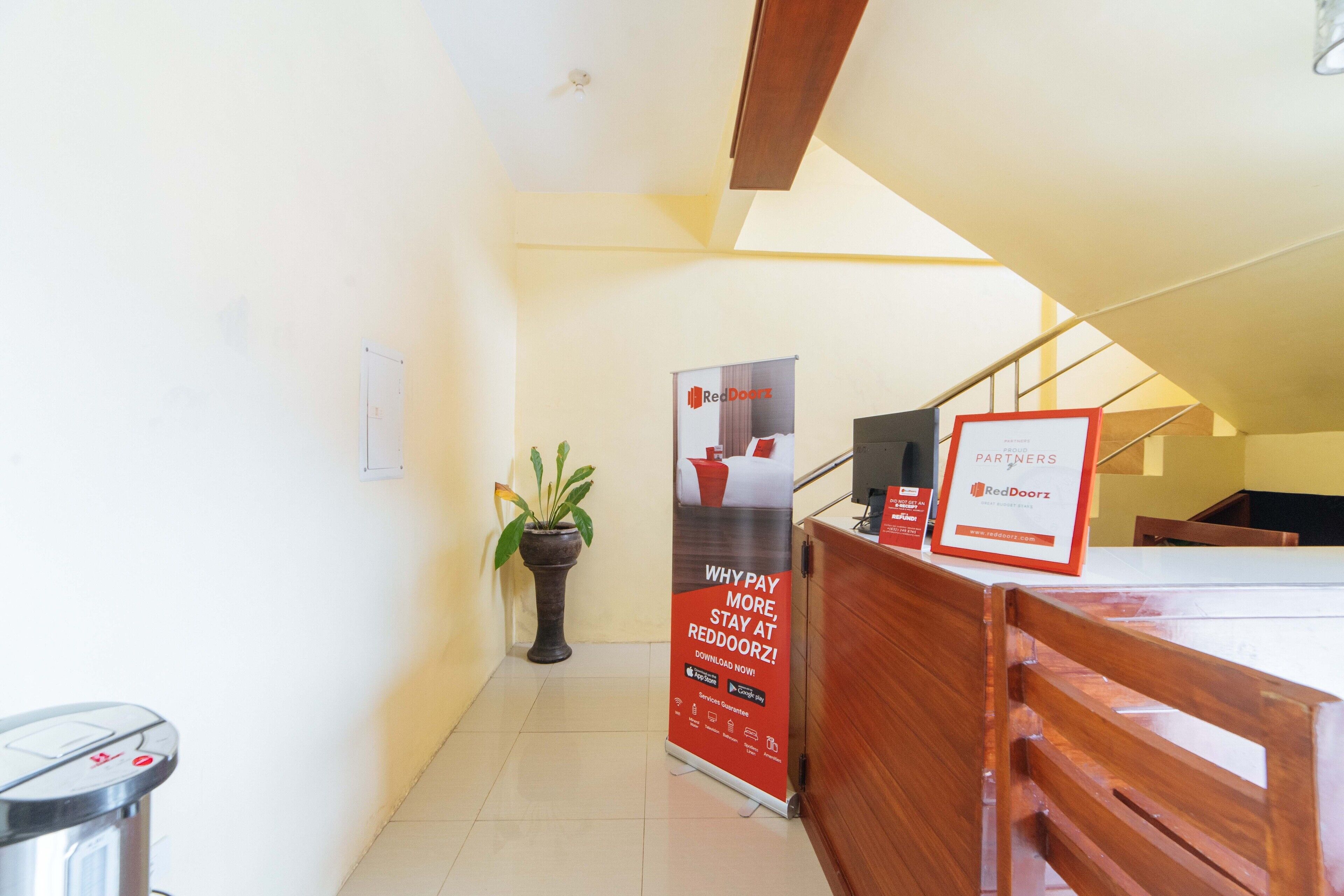 A reception area with a desk, a potted plant, and a RedDoorz sign.