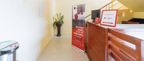 A reception area with a desk, a potted plant, and a RedDoorz sign.