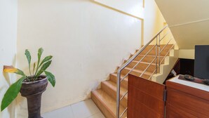 A staircase with wooden steps and metal railings, leading to a landing with a potted plant. - Reddoorz @ D Maagma Street - Vaccinated Staff (Kalibo)