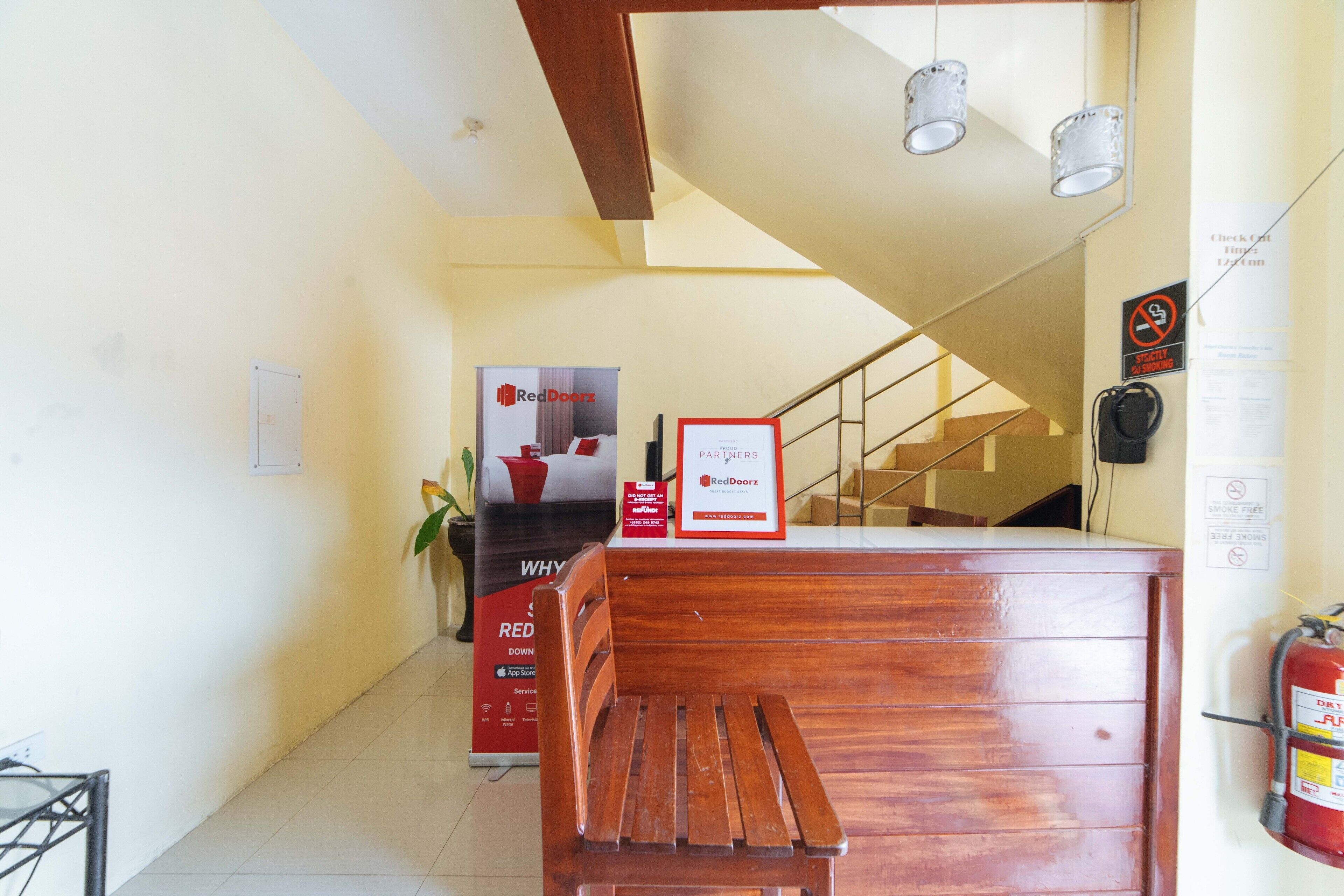 Un área de recepción con un banco de madera, un letrero de RedDoorz, una escalera y un extintor.