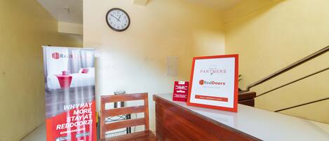 A reception area with a wooden desk, a clock on the wall, and promotional posters.