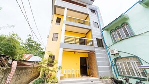 A multi-story building with a yellow facade, balconies, and a gated entrance. - Reddoorz @ D Maagma Street - Vaccinated Staff (Kalibo)