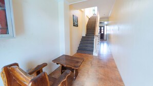 A hallway with a staircase, wooden benches, and a painting on the wall. - Reddoorz @ Old Buswang Road (Kalibo)