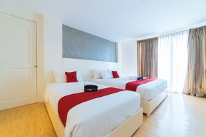A hotel room with two beds, a large window with curtains, and a door. - Reddoorz Plus @ Hotel Metro (Kalibo)