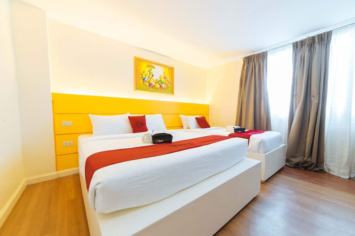 A hotel room with a large bed, a smaller bed, a painting on the wall, and a window with curtains.