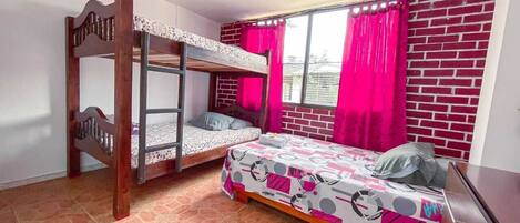 Una habitación con una cama litera, una cama individual, un escritorio y una ventana con cortinas.