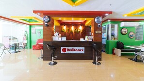 Een RedDoorz receptiebalie met een modern ontwerp, een groene wand en een plafond in rood en geel.