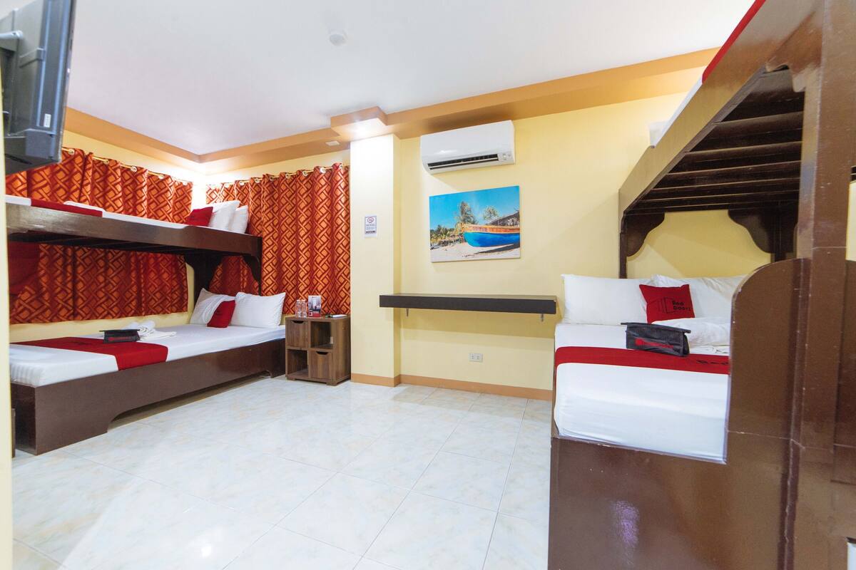 Une chambre d’hôtel avec deux lits, une télévision, un climatiseur et un tableau au mur.