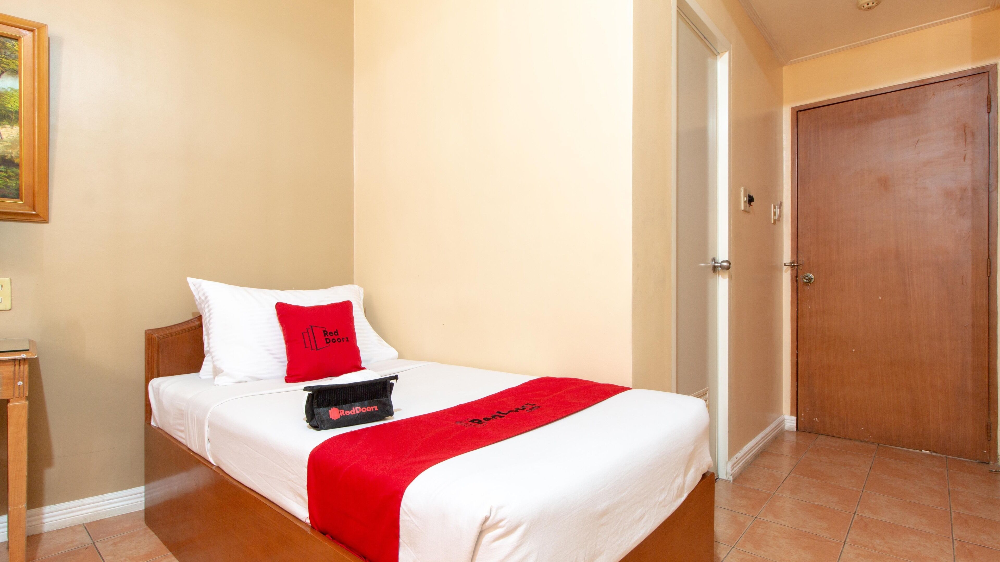 Ein Hotelzimmer mit einem Bett, einer Tür und einem Fliesenboden.
