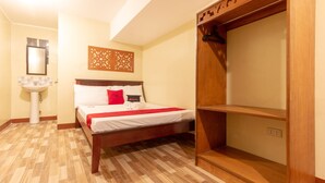 A hotel room with a wooden bed, a white sink, and a wooden wardrobe. - RedDoorz near PNR Espana Station (Manila)