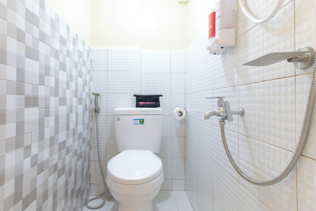 Ein Badezimmer mit Toilette, Dusche und einem an der Wand befestigten Toilettenpapierhalter.