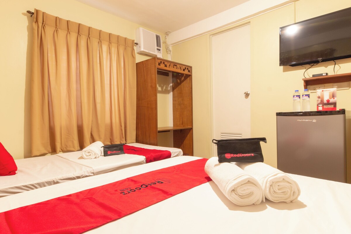 Ein Hotelzimmer mit zwei Betten, einem Fernseher, einer Minibar und einem Kleiderschrank.