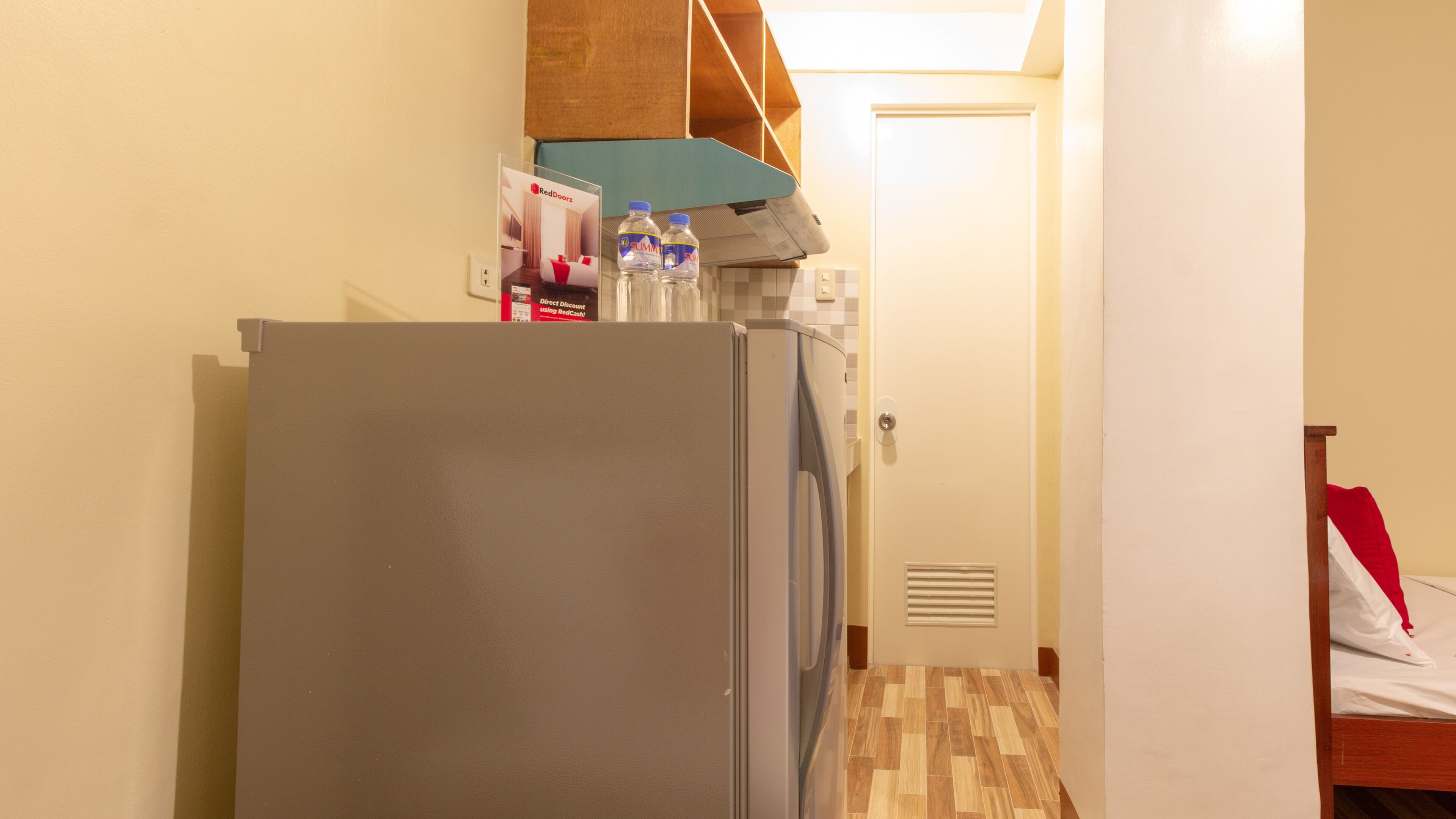 Eine kleine Küche mit Kühlschrank, Mikrowelle und Wasserspender auf der Arbeitsfläche.