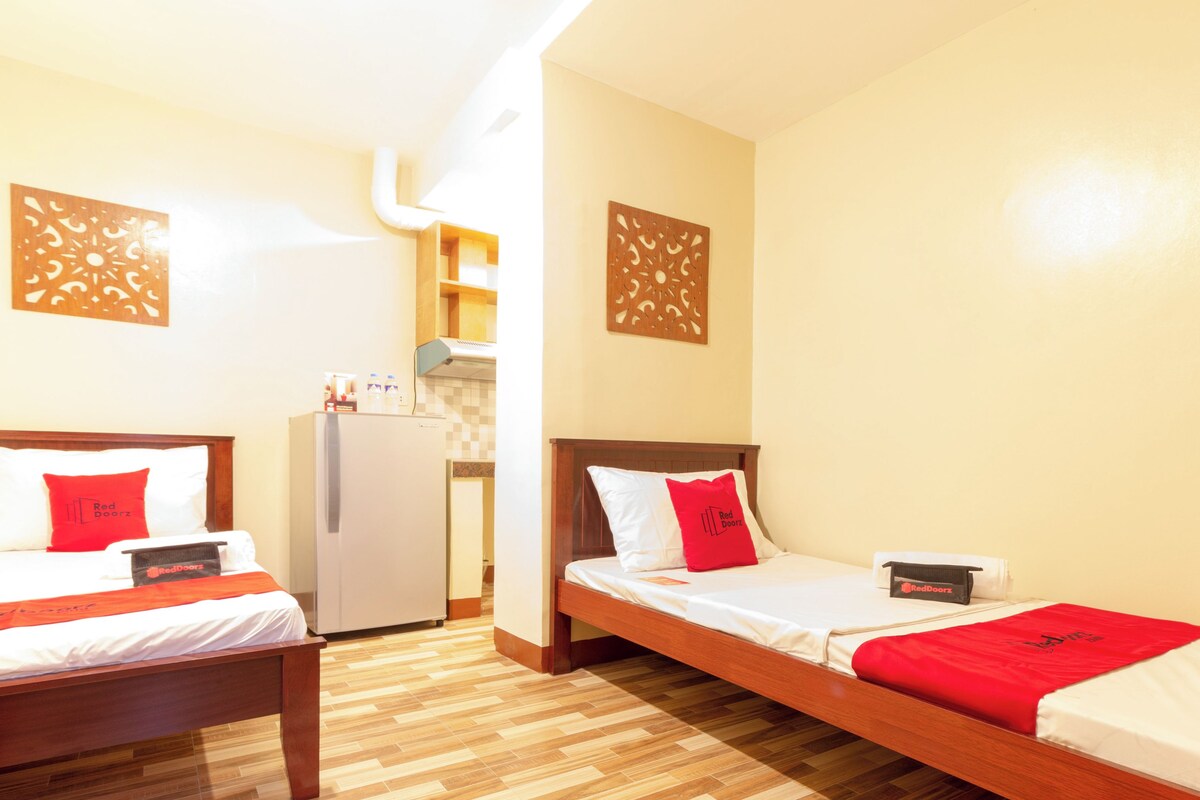 Ein Hotelzimmer mit zwei Betten, einem Kühlschrank und einer kleinen Küchenzeile.
