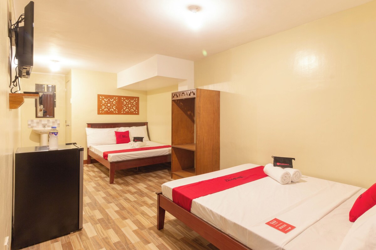 Ein Hotelzimmer mit zwei Betten, einem Holzschrank, einem Schreibtisch und einem Spiegel.