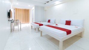 A hotel room with two beds, each with white bedding and red accents, a small table with a chair, and a TV mounted on the wall. - RedDoorz @ DBuilders Rooms Lower Bicutan (Taguig)