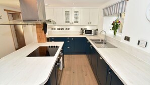 Una cocina moderna con armarios blancos, una estufa negra y piso de madera.