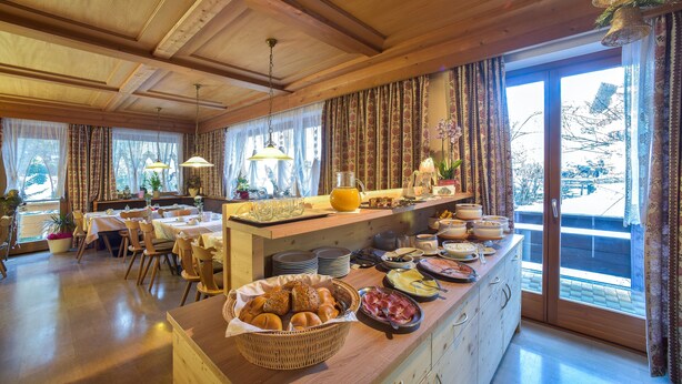 Un buffet de petit-déjeuner proposant une variété de plats et un espace repas avec des tables et des chaises en bois.