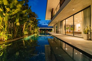 A modern building with a swimming pool, glass doors, and indoor plants. - Akala Villa, Hoi An, Luxury 6 bedrooms, Superb Rivers View, Hoi An Ancient Town (Hội An)