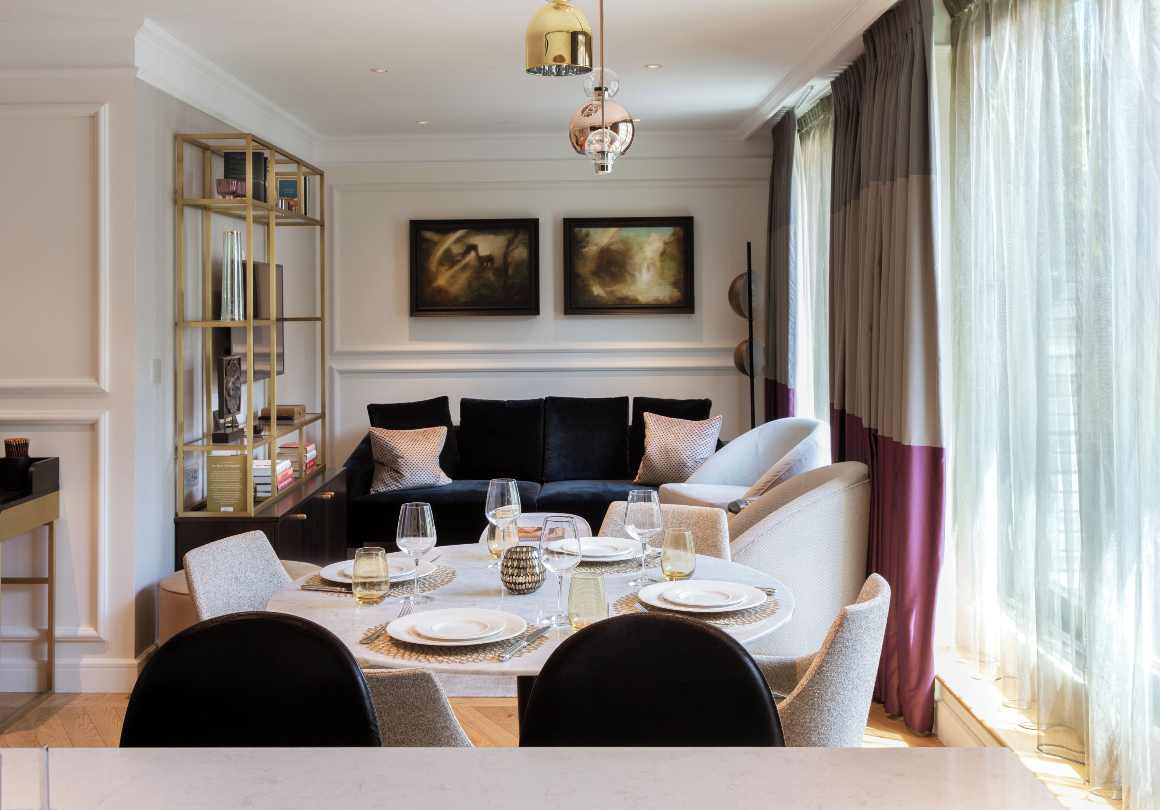 A dining area with a table set for four, a sofa, and a bookshelf.