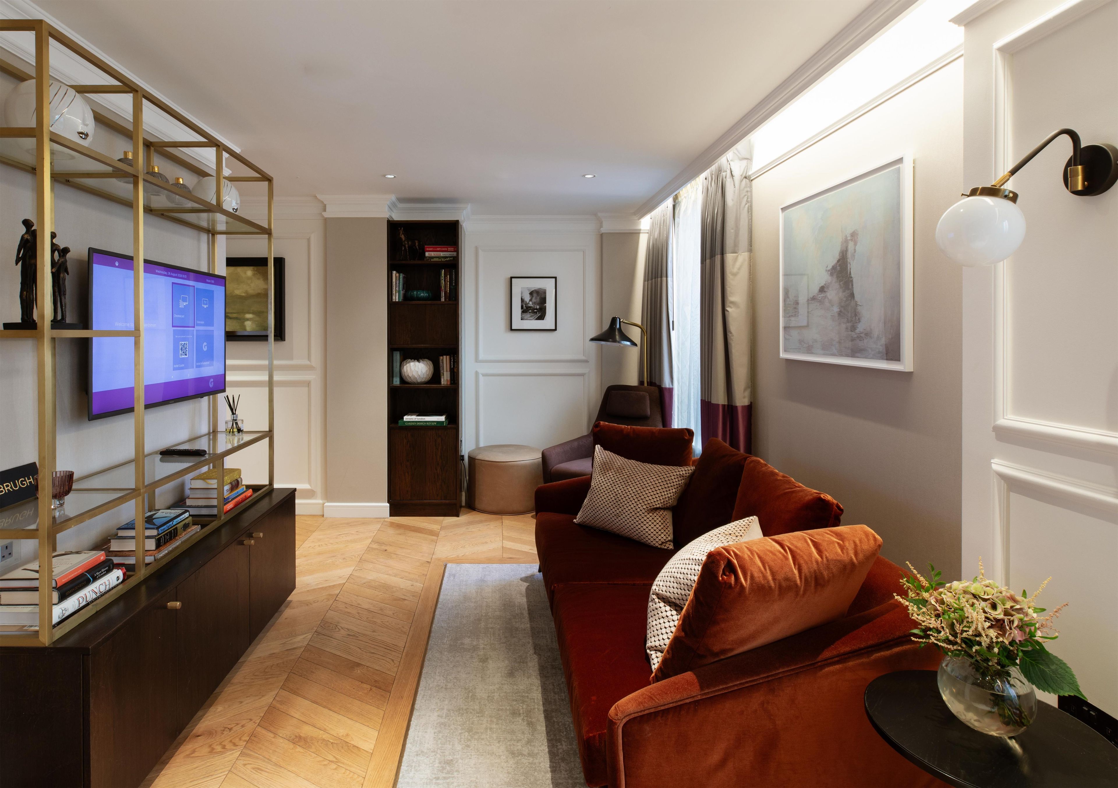 A modern living room with a sofa, a television, a bookshelf, and a decorative lamp.
