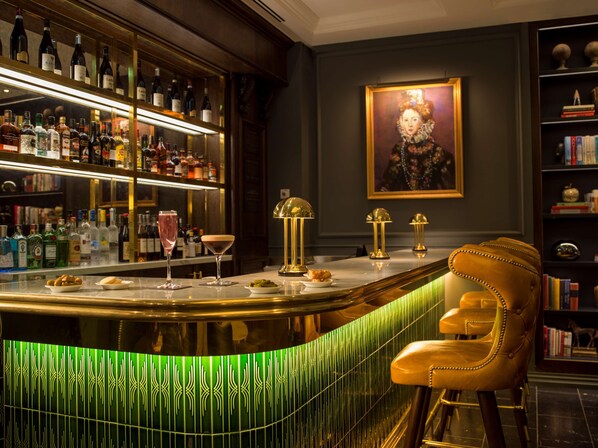Um bar com bancada de padrão verde, balcão dourado e uma cadeira dourada.