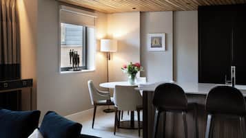 A modern dining area with a round table, two chairs, a lamp, and a window with curtains.
