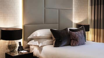 A hotel room with a large bed, a nightstand with a lamp, and a modern headboard.