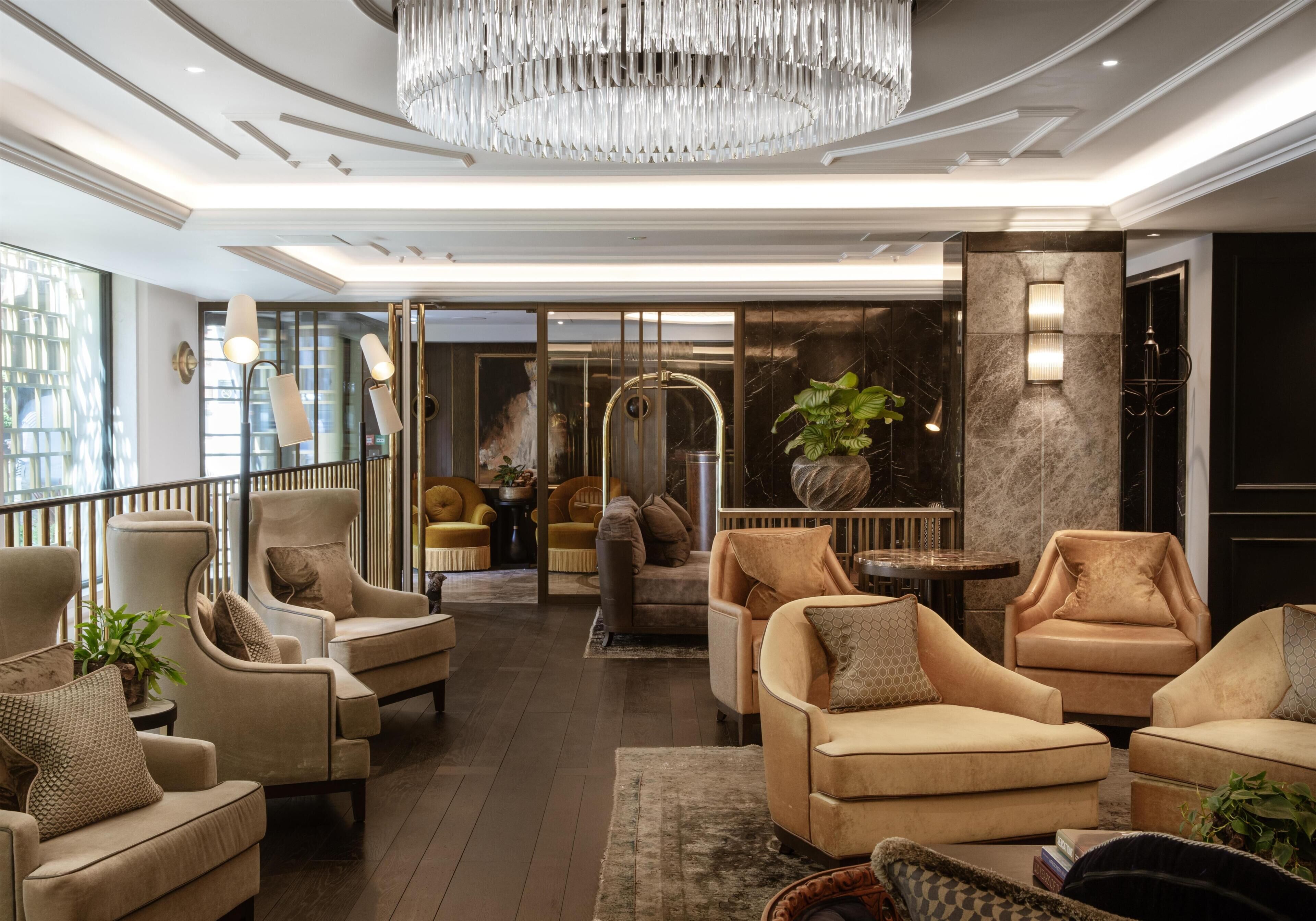 A spacious lobby with multiple seating areas, a grand chandelier, and a modern entrance with glass doors.