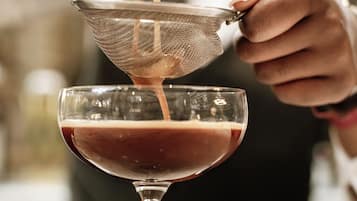 A person pouring a liquid into a glass with a strainer.