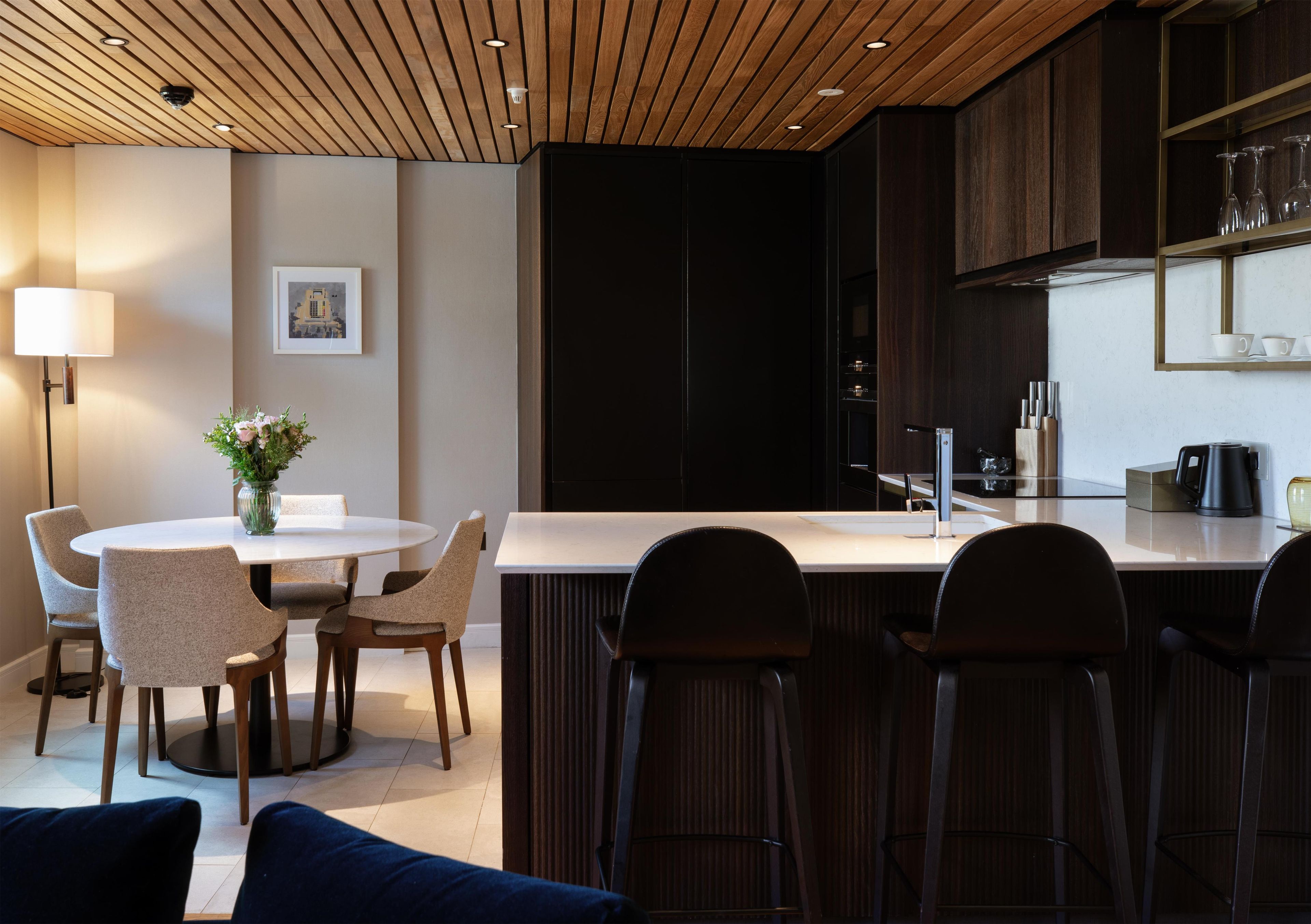 A modern kitchen with a central island, bar seating, and a dining area with chairs and a table.