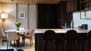 A modern kitchen with a central island, bar seating, and a dining area with chairs and a table.